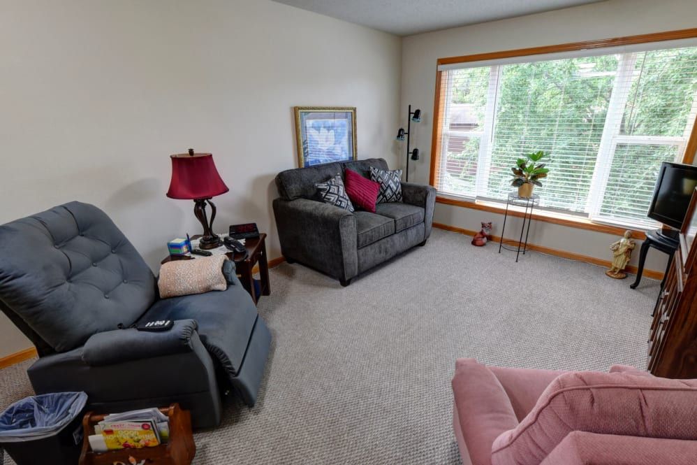 A cozy living room with a sofa, armchair, and large window.