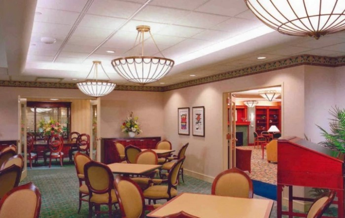 A well-lit room with tables and chairs, featuring elegant chandeliers and decorative elements.