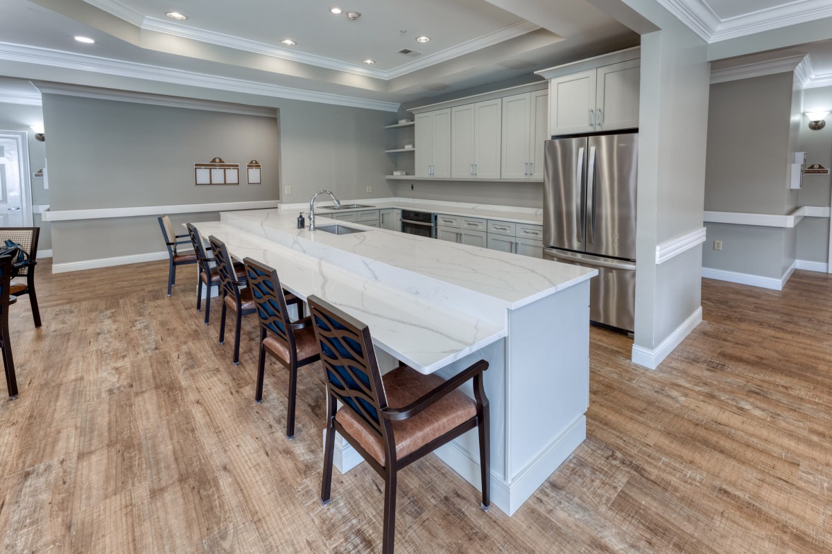 A modern kitchen featuring a large island with bar stools, stainless steel appliances, and wood flooring.
