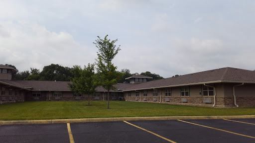 A view of a residential building surrounded by trees and a parking lot.