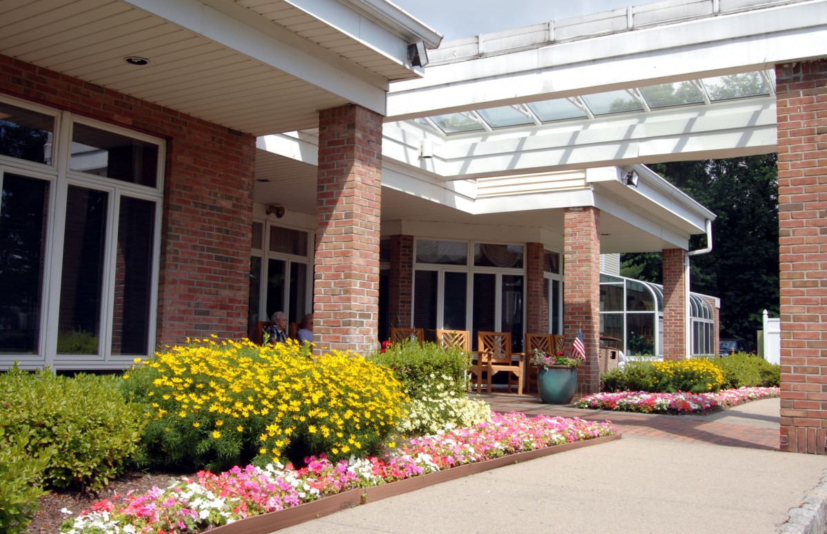 A well-landscaped building entrance with brick pillars and colorful flowerbeds.
