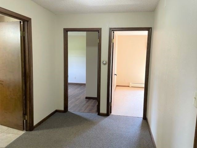 A hallway in an apartment with multiple open doors leading to empty rooms.