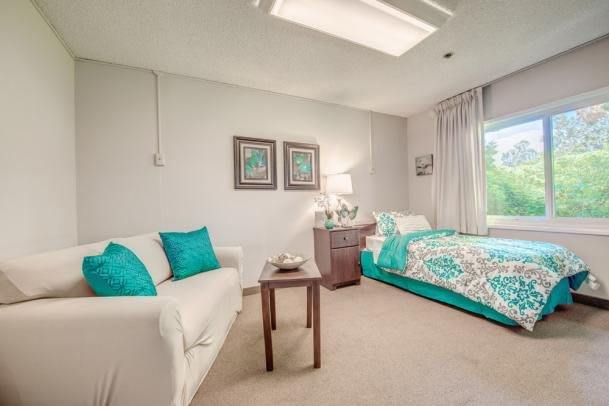 A modern bedroom with teal accents, featuring a comfortable bed, sofa, and tasteful decor.