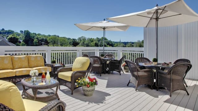 A sunny outdoor patio with wicker seating and large umbrellas provides a relaxing environment.