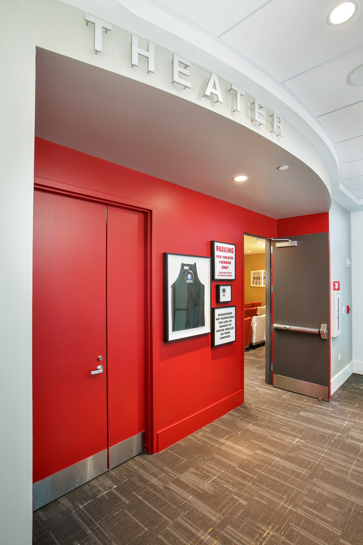 A modern hallway with red walls and an exit door.
