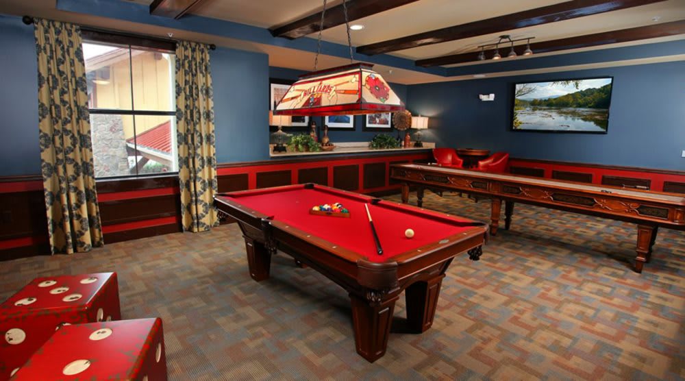 A stylish game room featuring a pool table with red felt and elegant lighting.