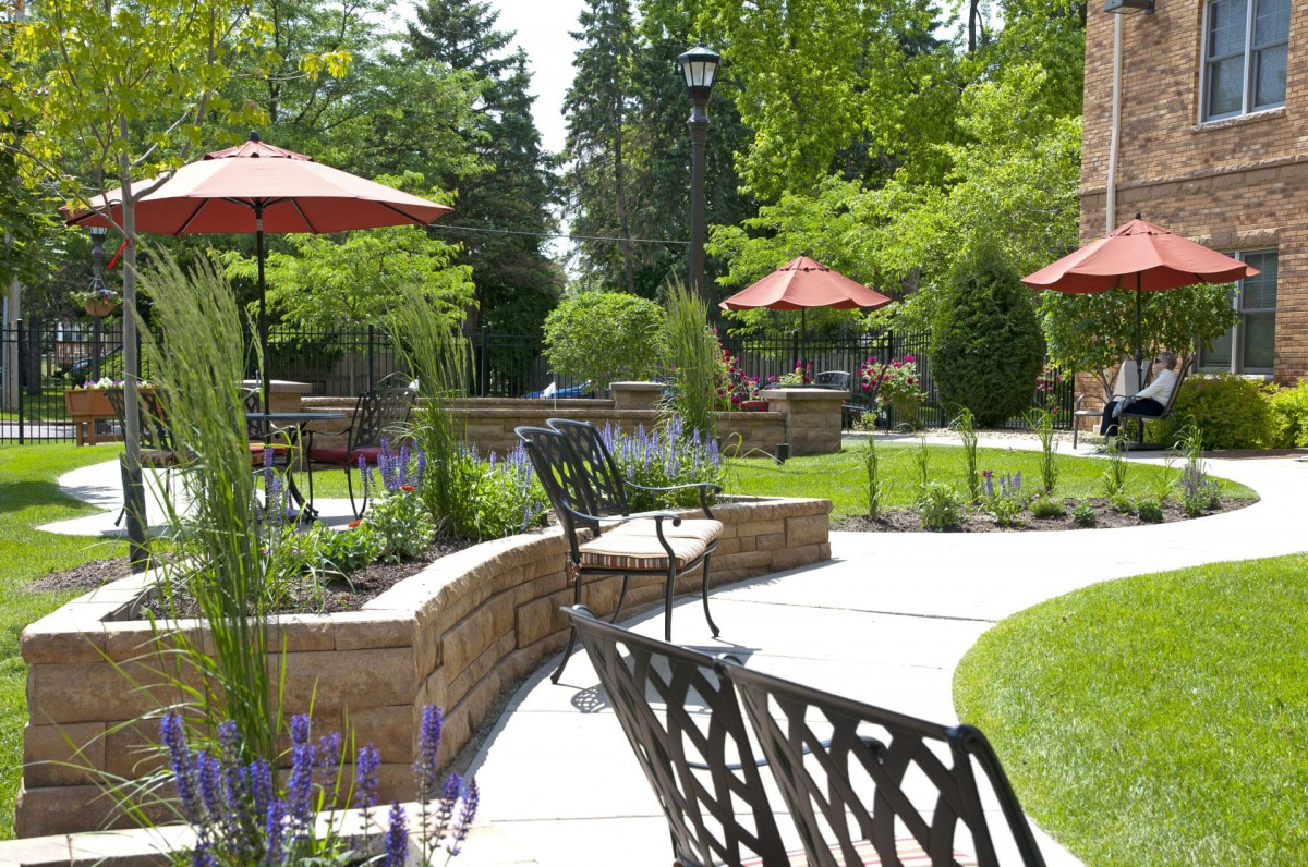 A scenic outdoor garden area with paved walkways, seating, and umbrellas offering a peaceful setting.