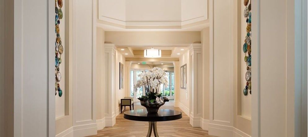 A beautifully decorated hallway with a central table adorned with flowers.