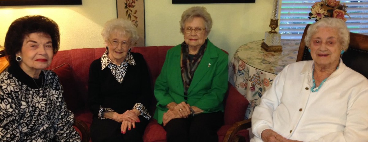 Two elderly women sitting on a couch in a living room.