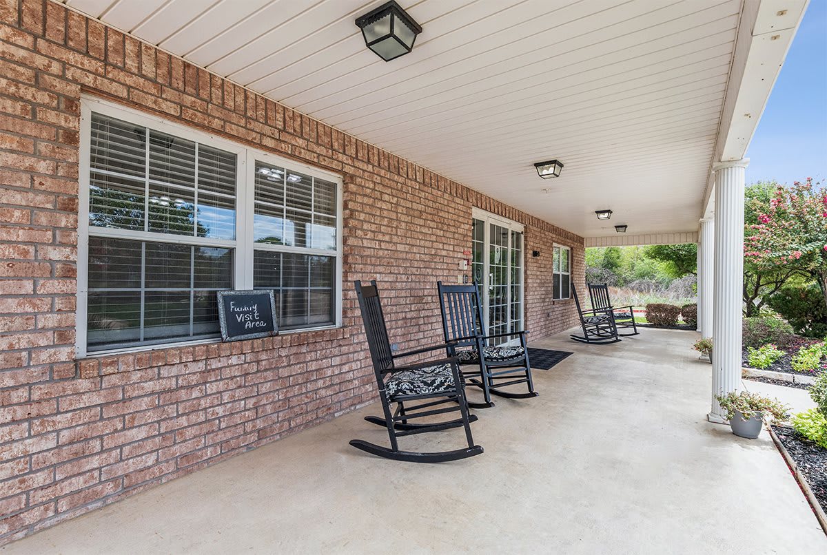 A cozy covered porch with rocking chairs against a brick wall.
