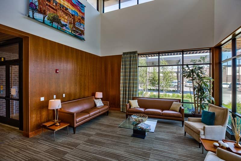 A modern living room with leather sofas, a coffee table, and large windows.