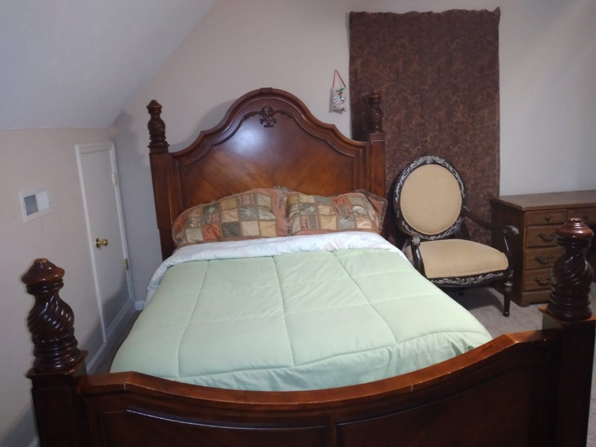 A cozy bedroom featuring a bed with a wooden headboard and a comfortable chair.