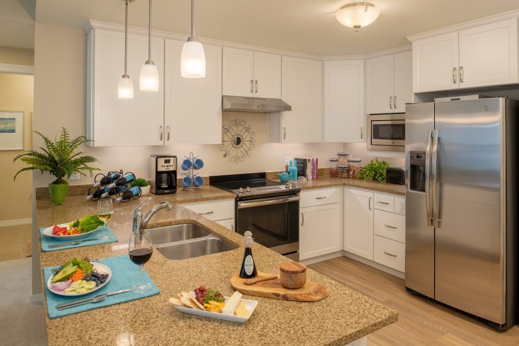 A modern kitchen featuring white cabinets and granite countertops, equipped with stainless steel appliances and ambient lighting.