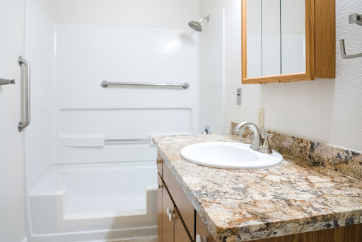 A modern bathroom featuring a granite countertop sink and a spacious shower area.