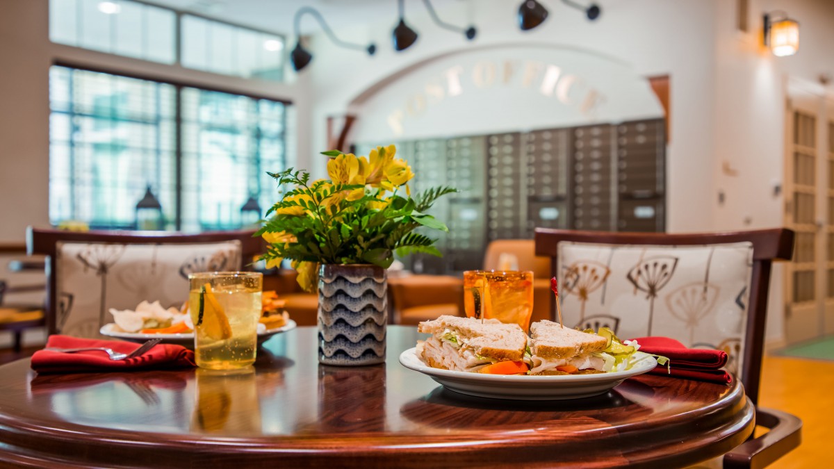 A cozy restaurant table setting with a sandwich and drinks.
