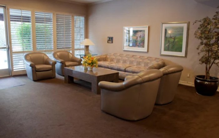 A cozy living room with a large sofa, several armchairs, and a coffee table.