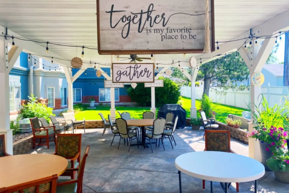 A cozy outdoor patio area with tables and chairs, decorated with charming signs that read 'together is my favorite place to be'.