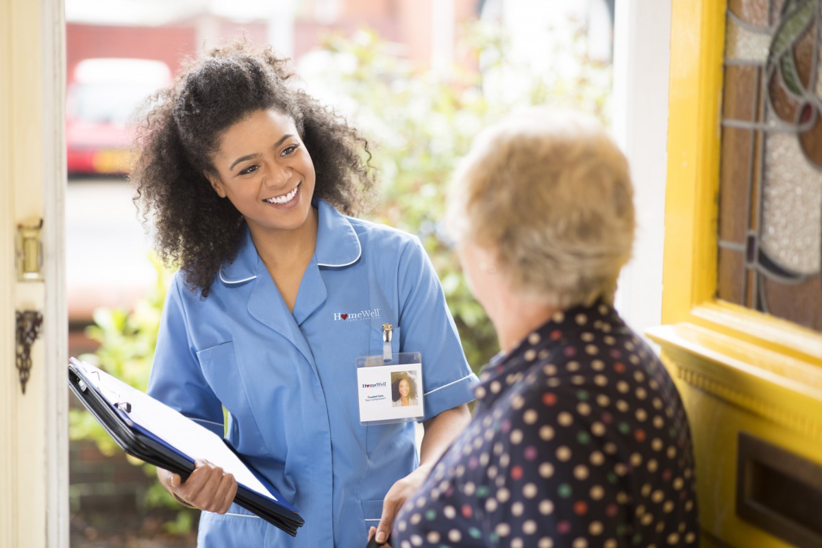 A nurse smiling while interacting with an elderly patient.
