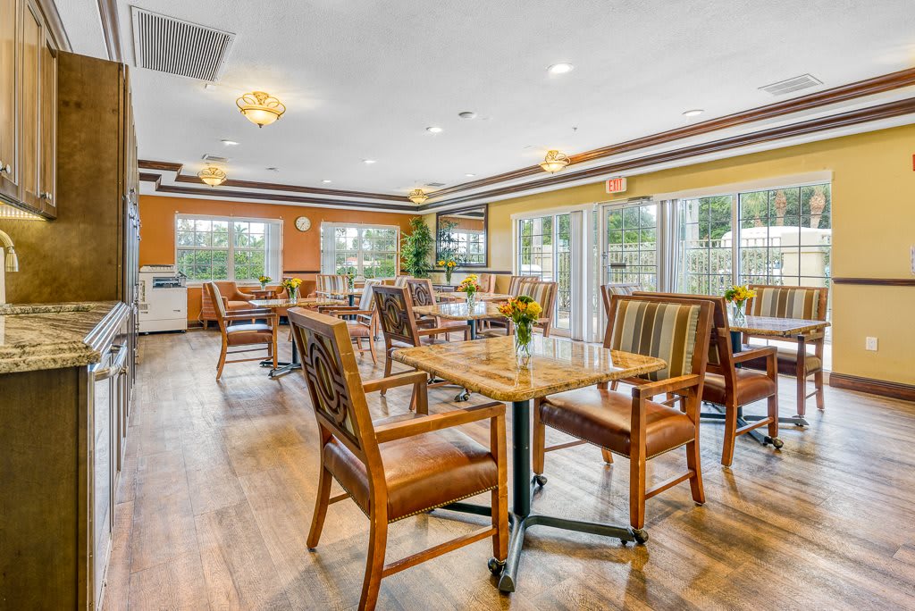 A spacious dining area with wooden tables and chairs, well-lit by large windows.