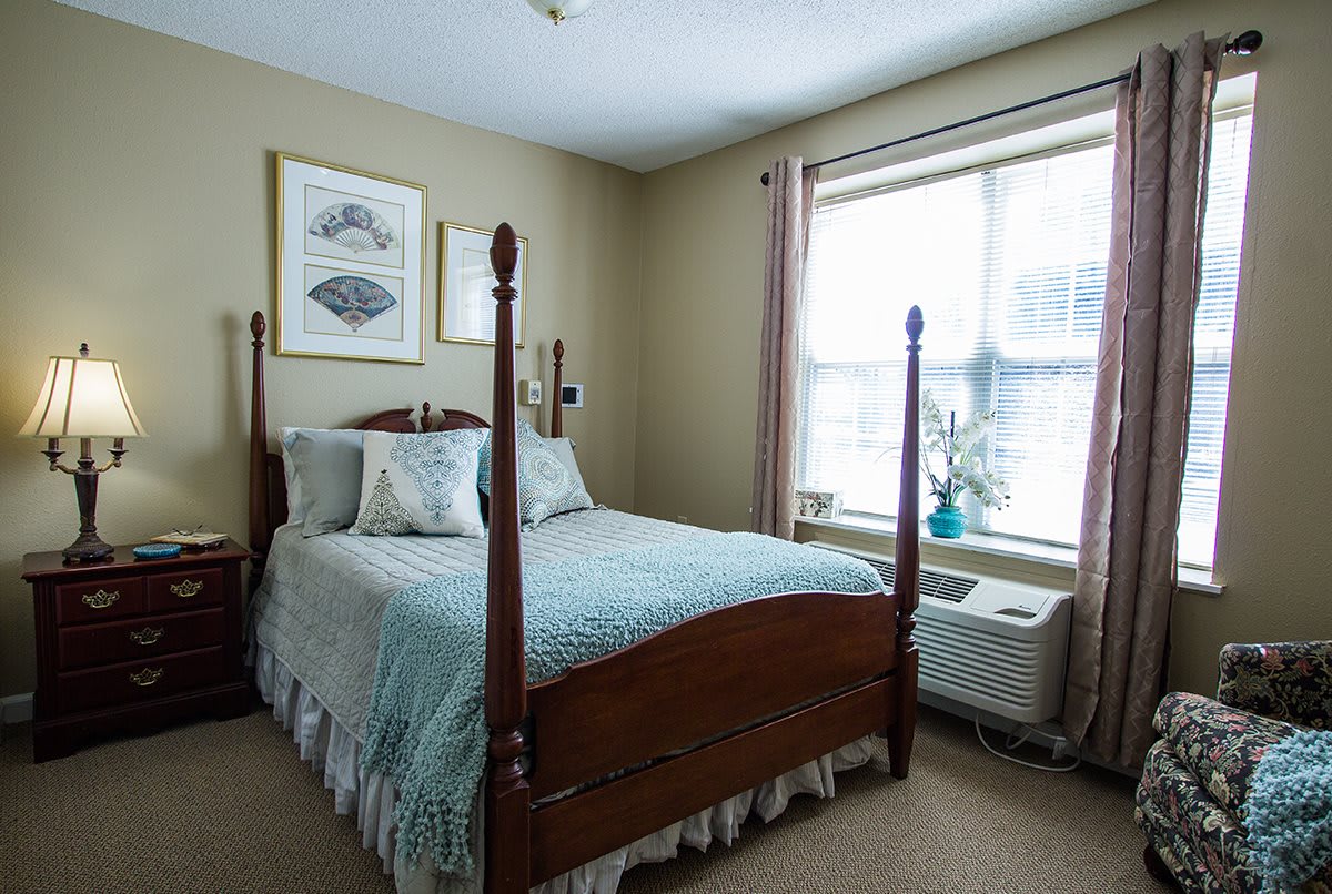 A cozy bedroom with a four-poster bed and large window.