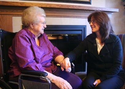 A touching moment between two women, sharing smiles and holding hands in a cozy indoor environment.