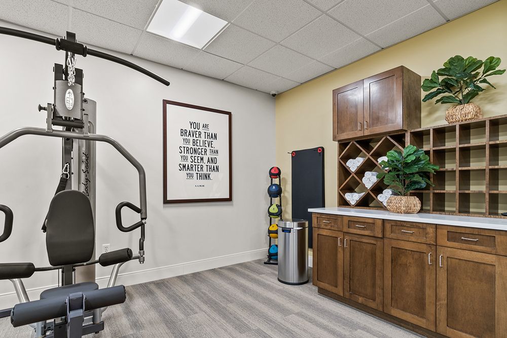 A stylish home gym with exercise equipment and a wine rack, featuring modern decor and wall art.