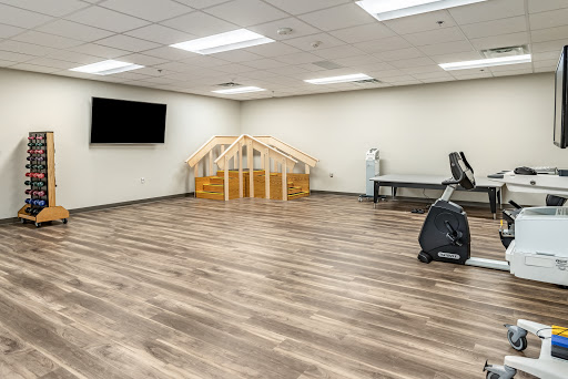A spacious therapy room equipped for rehabilitation exercises, featuring a wooden structure and fitness equipment.