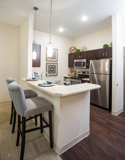 A modern kitchen featuring an open layout with stylish bar stools and stainless steel appliances.