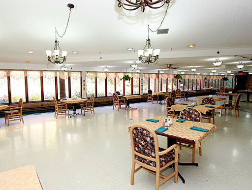A bright and spacious dining area featuring tables and chairs, illuminated by elegant chandeliers.