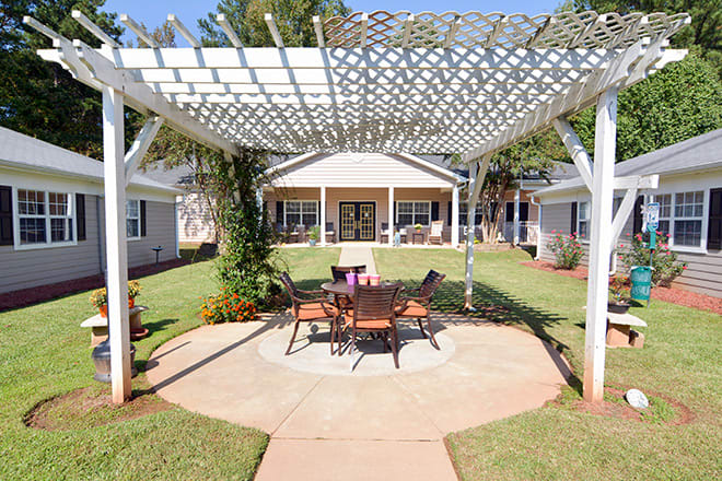 A charming backyard with a pergola and outdoor seating area, surrounded by a well-maintained lawn.