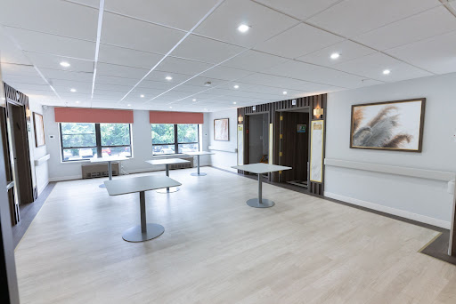 A spacious, well-lit conference room featuring modern tables and a minimalist design.