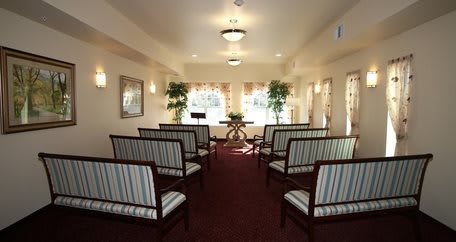 A small chapel with rows of striped seating and warm lighting.