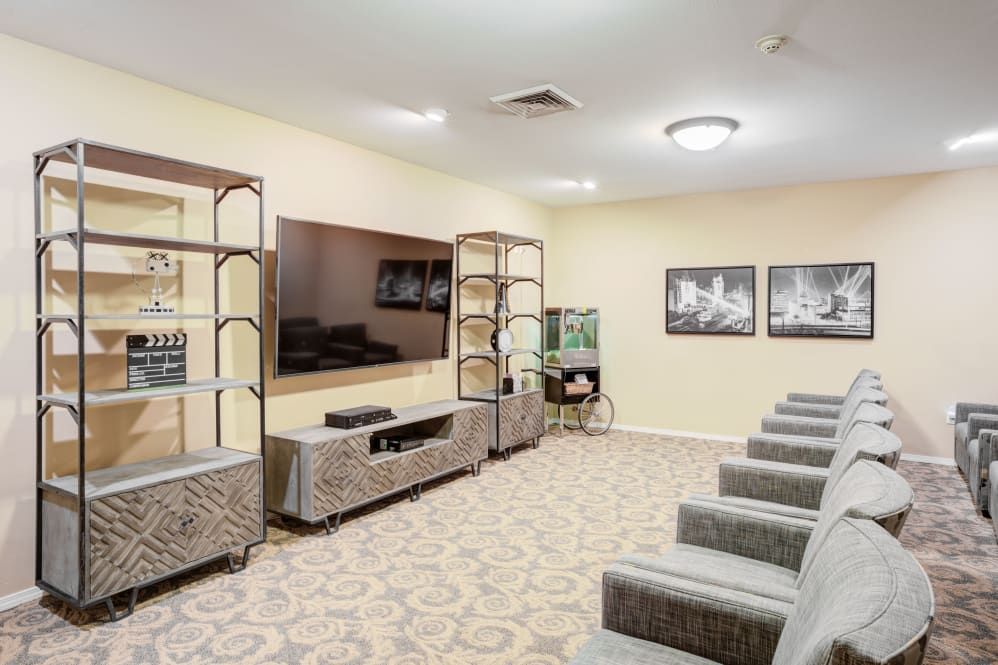 A cozy home theater room with comfortable seating, a large television, and decorative shelving.