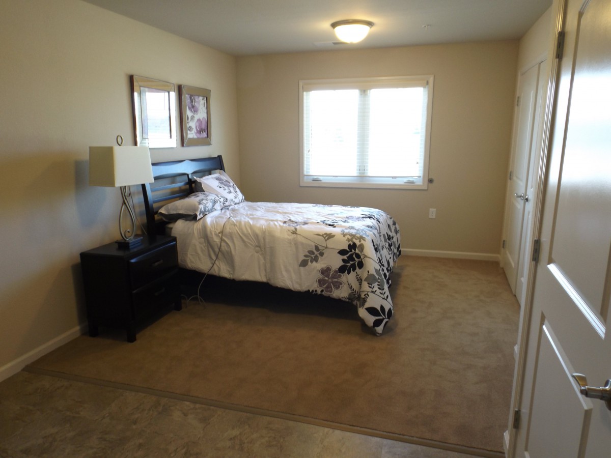 A cozy bedroom with a bed, nightstand, and carpeted floor.
