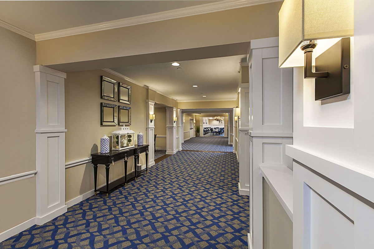 A well-decorated hotel hallway with patterned carpet and wall artwork.