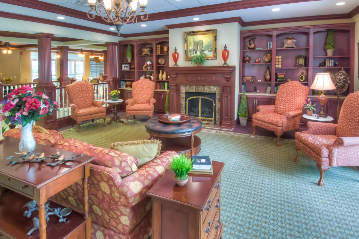 A traditional living room with elegant furniture, a central fireplace, and built-in bookshelves.