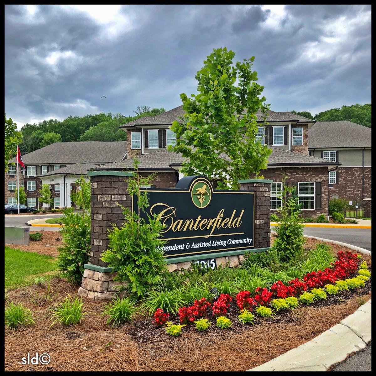 Entrance to a residential community with landscaped gardens and a welcoming sign.