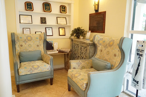 A cozy waiting area featuring elegant chairs, decorative awards on the shelf, and a touch of greenery.