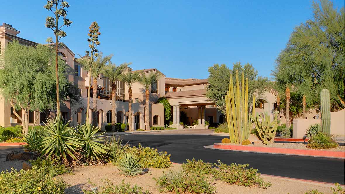 A desert resort with palm trees and cacti in the foreground.