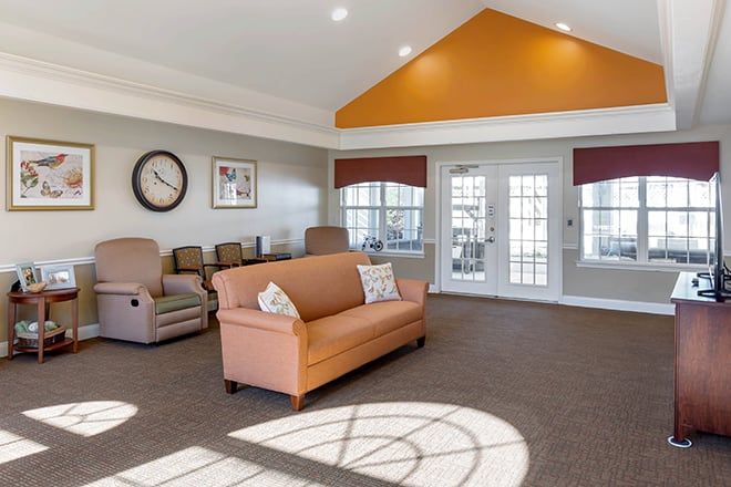 A cozy and spacious living room with a sofa, recliners, and large windows letting in natural light.