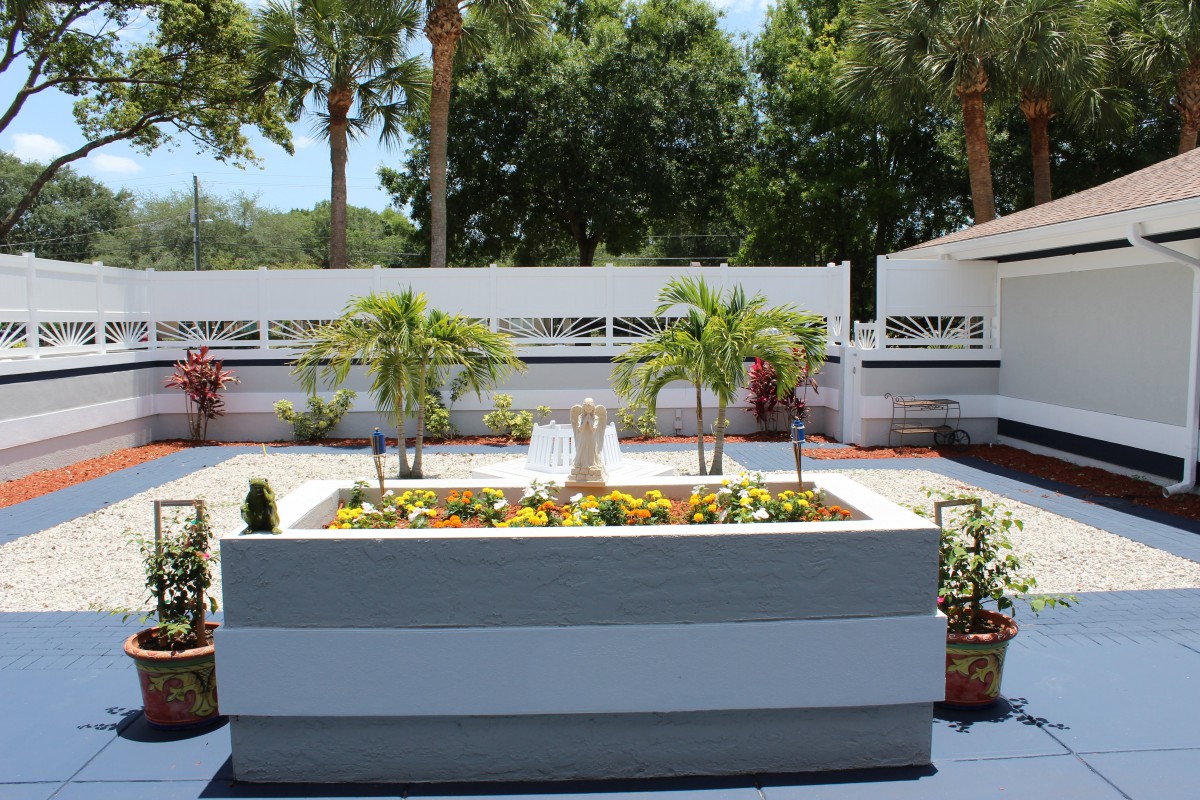 A beautifully landscaped garden featuring palm trees and colorful flowers on a sunny day.