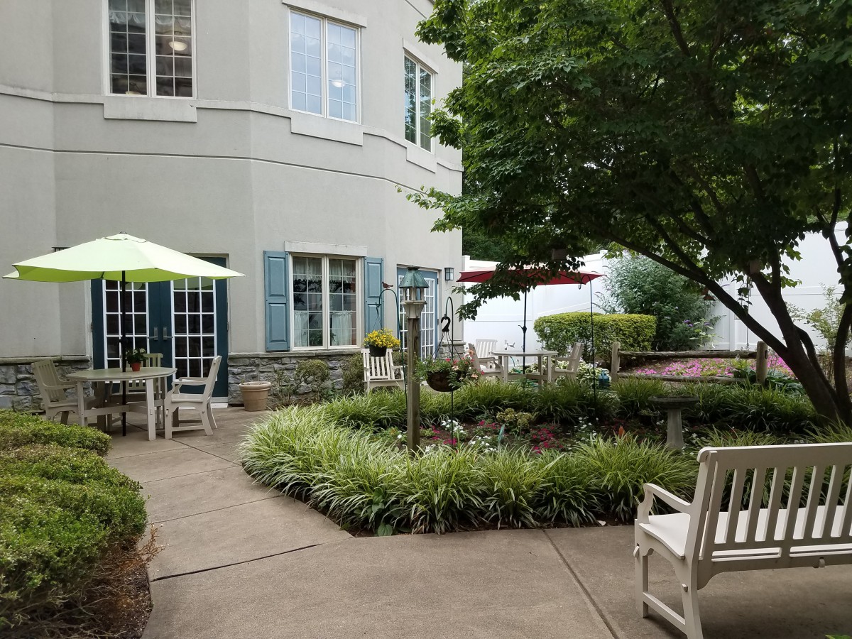 A serene outdoor patio area with seating and lush greenery.