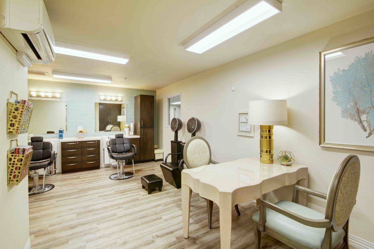 A well-lit beauty salon interior with a hair styling station and manicure table.