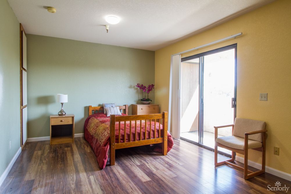 A modern minimalist bedroom with wooden furniture and ample natural light.