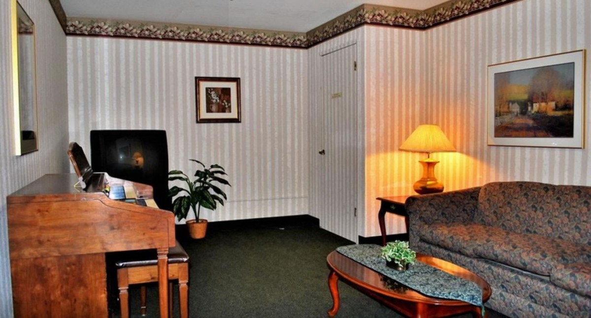 A cozy living room with a chair, sofa, coffee table, and a lamp casting a warm glow.