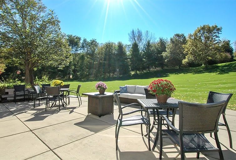 A sunny patio with outdoor seating and a lush garden backdrop.