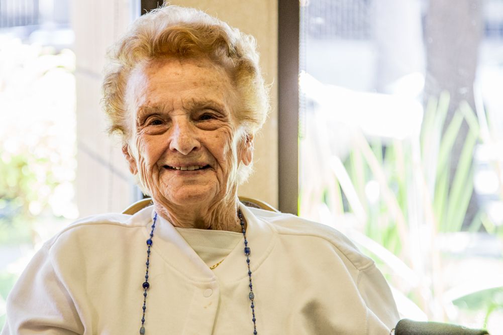 An elderly woman smiling warmly while seated indoors.