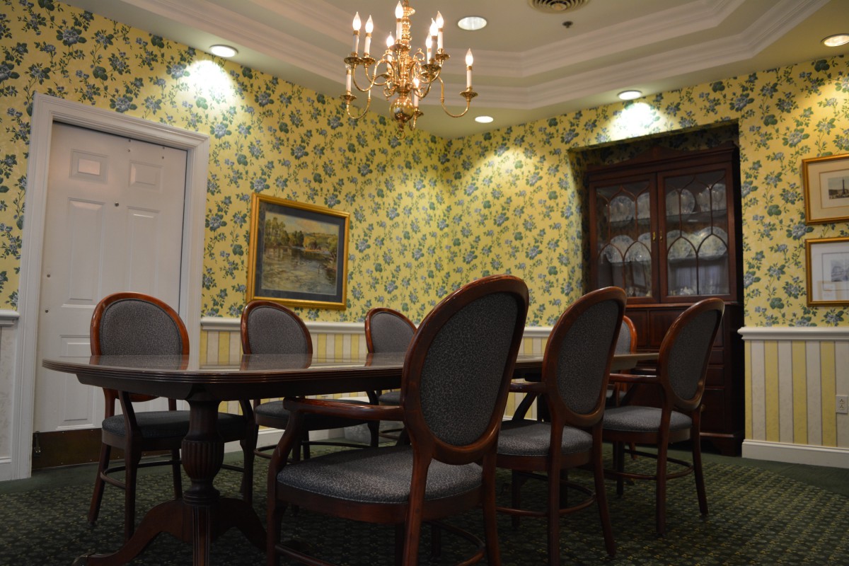 A classic conference room with a large table and chairs under a chandelier.