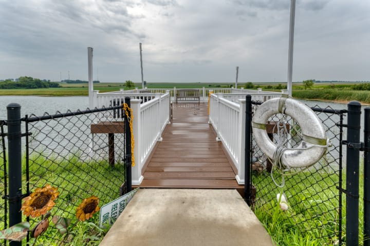 A wooden dock leading to the water under a cloudy sky.