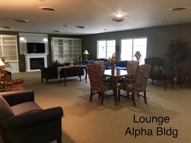 A cozy lounge area in Alpha Block with comfortable seating and a fireplace.